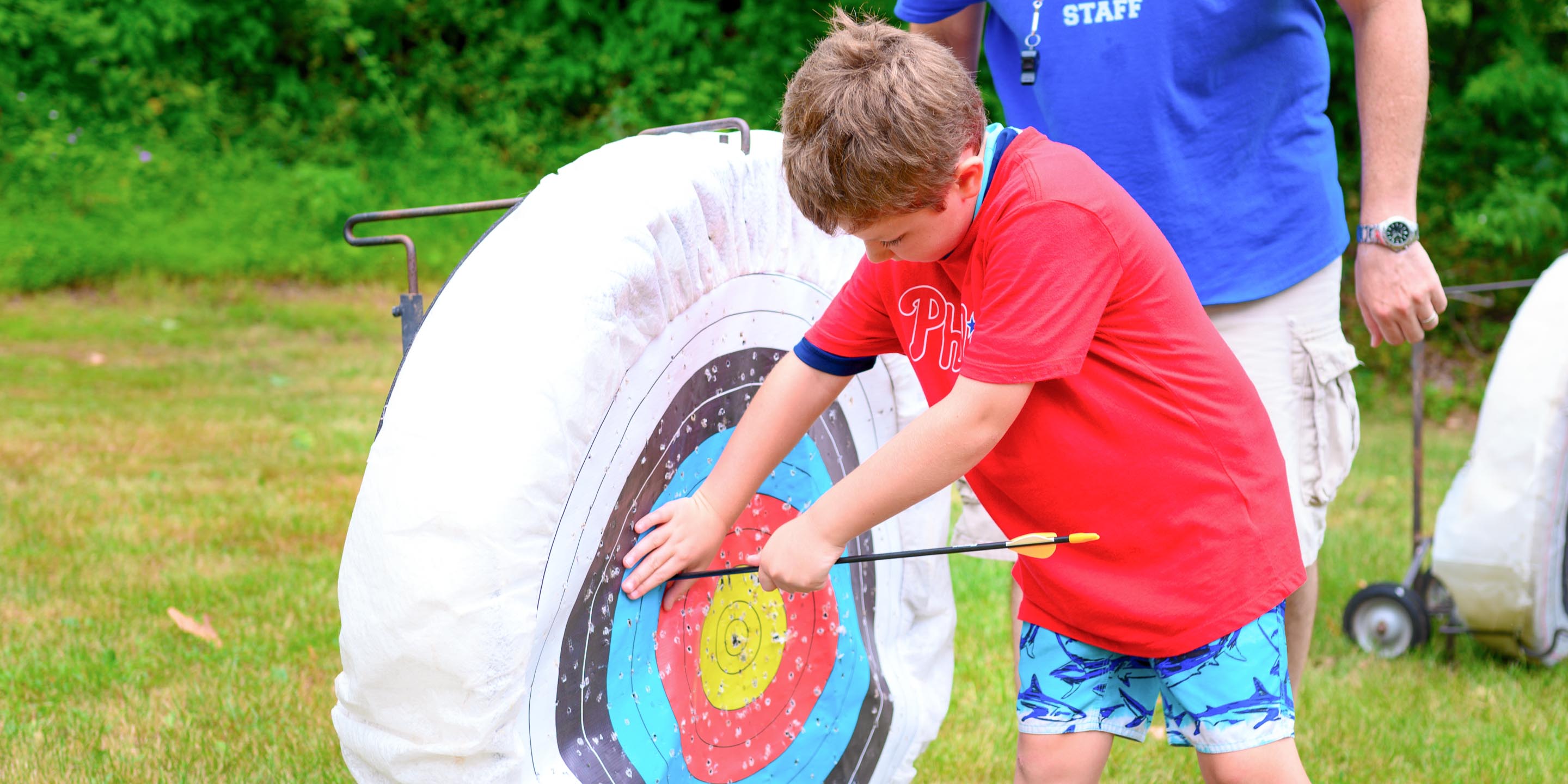 Boy pulling archery arrow out of target