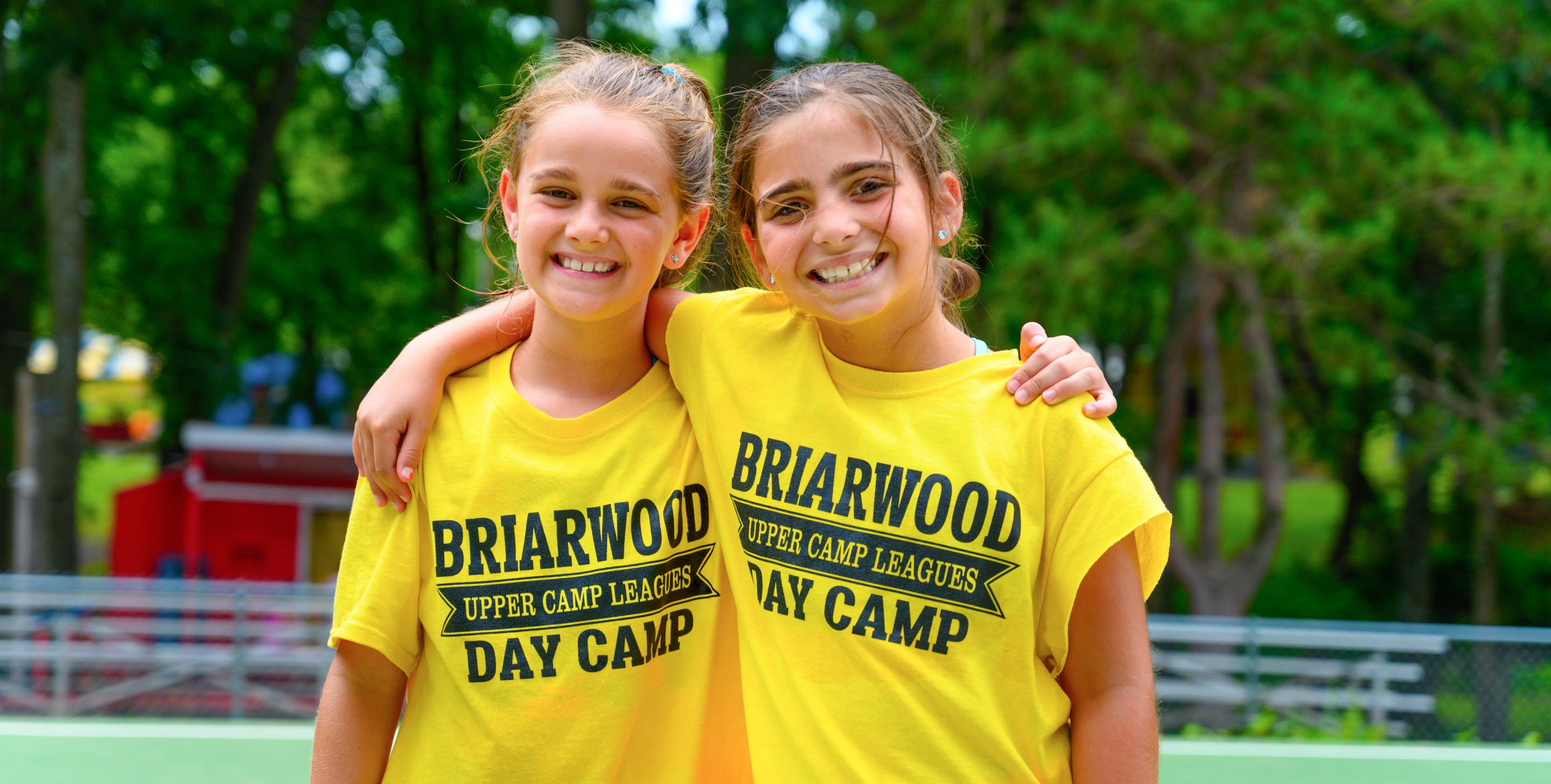 Two girls wearing camp shirts and smiling