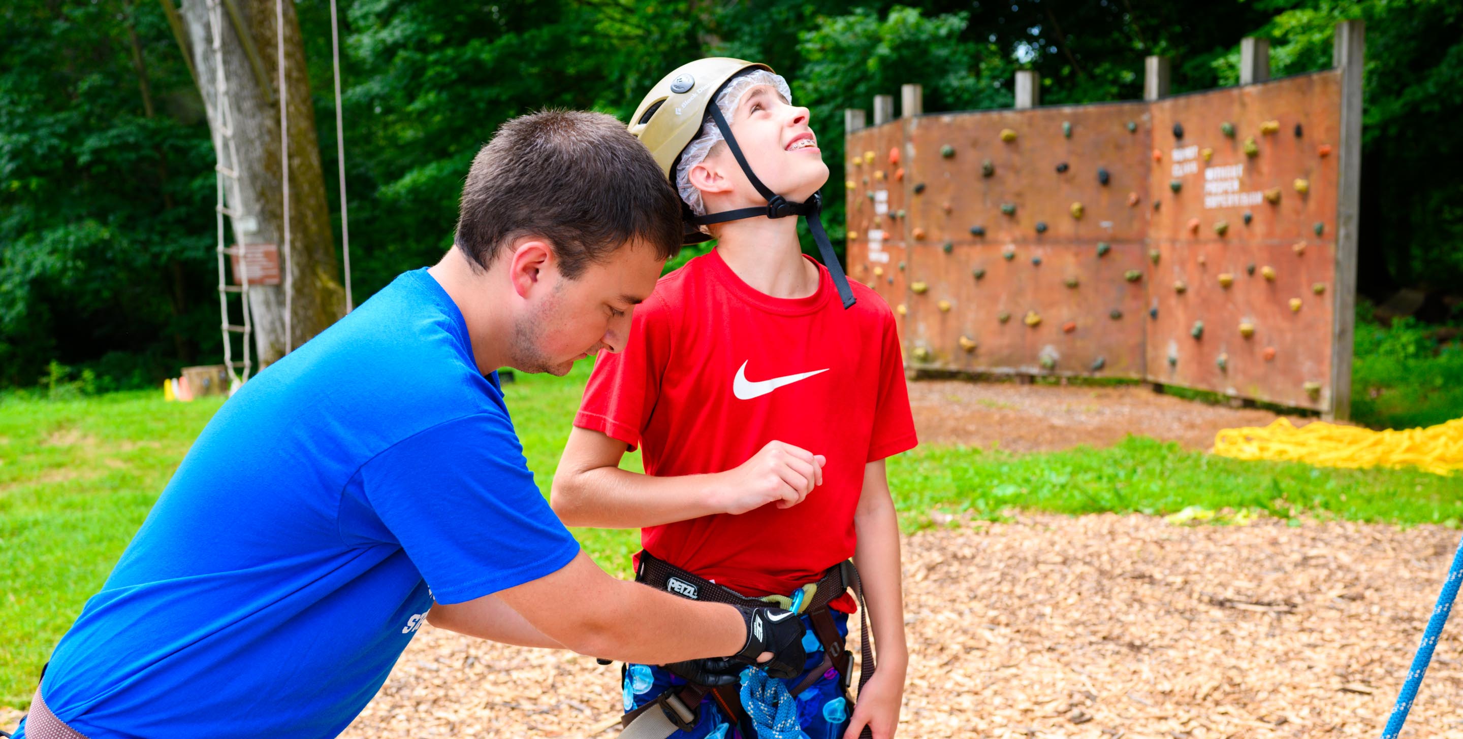 Camper looking at climbing tower and wearing helmet