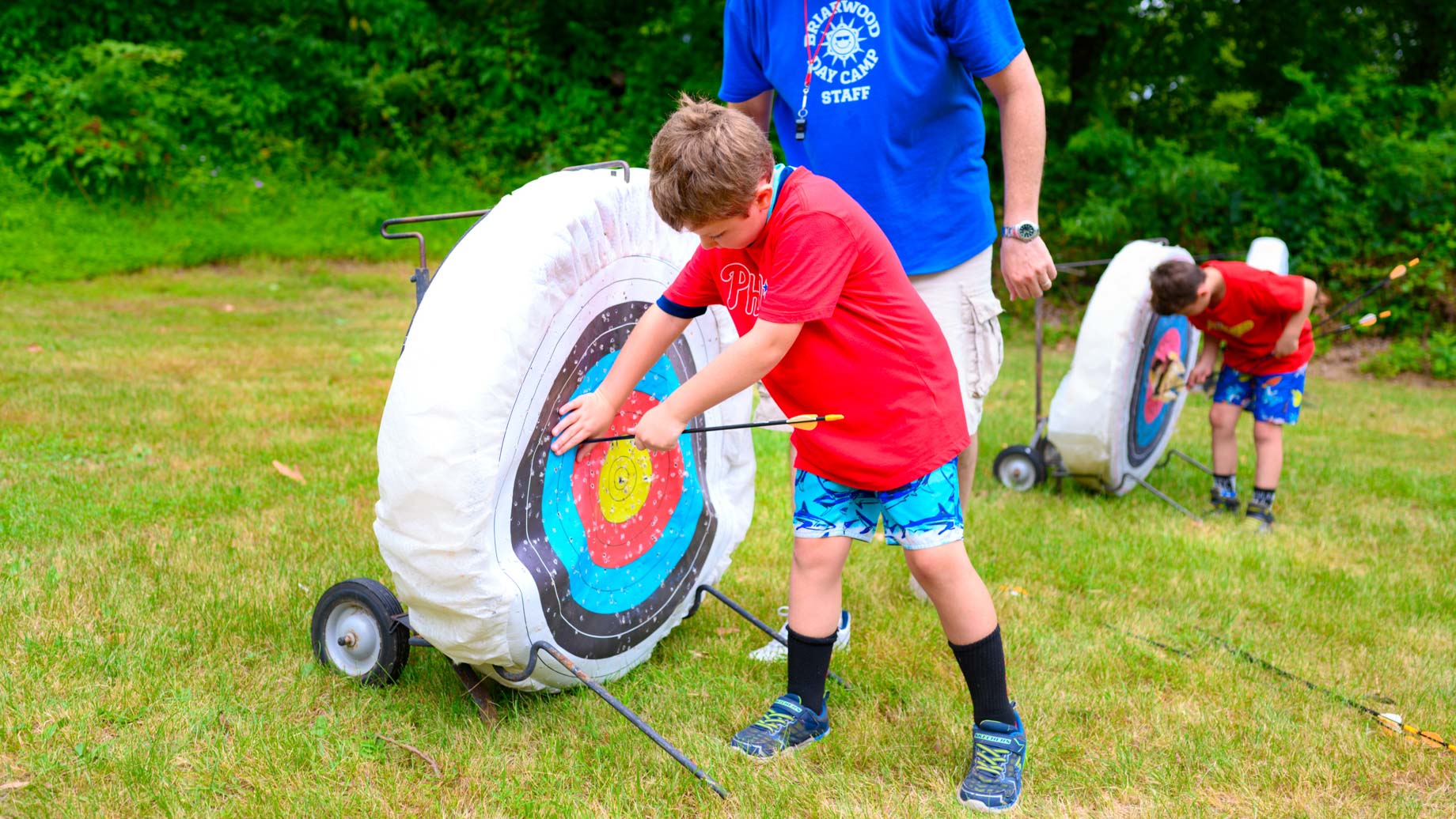 Camper taking archery arrow out of target