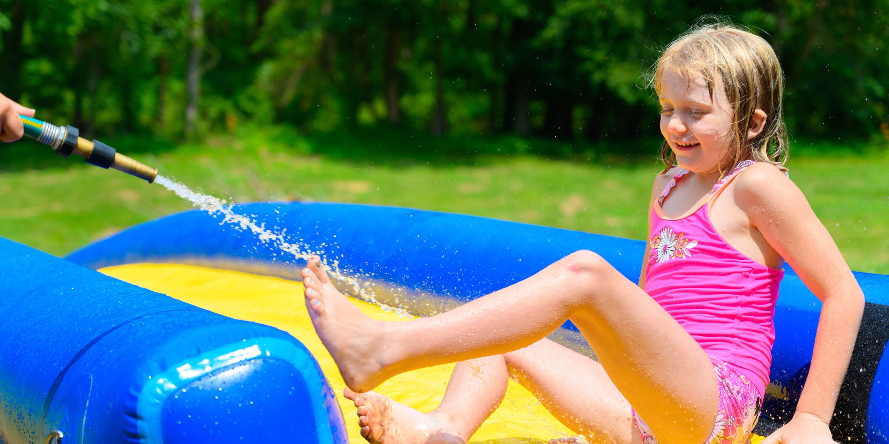 Girl being sprayed by water hose on waterslide